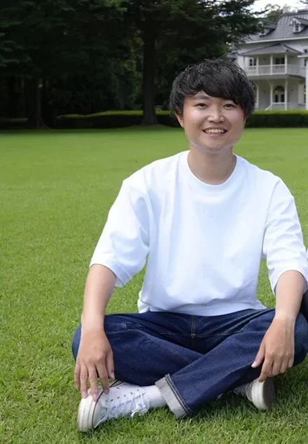 芝生の上で笑顔を見せる石﨑陽さん